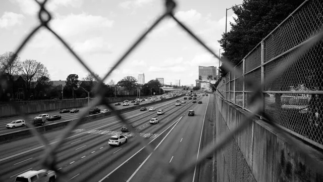 Autobahn hinter einem Maschendrahtzaun in Schwarz-Weiß – Anreise mit dem Auto zum Flughafen Hamburg