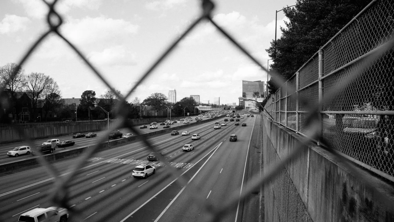 Motorway behind a wire mesh fence in black and white – driving to Hamburg Airport