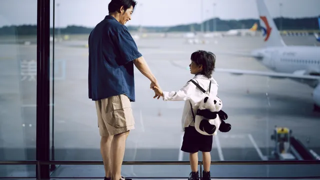 Vater und Kind an der Fensterfront mit Blick auf ein Flugzeug – mit Familie und Gepäck zum Flughafen Berlin (BER)