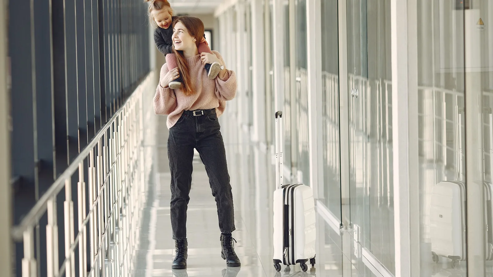 Mère avec enfant et valise dans un couloir d'aéroport – en famille et avec des bagages à l'aéroport de Hambourg