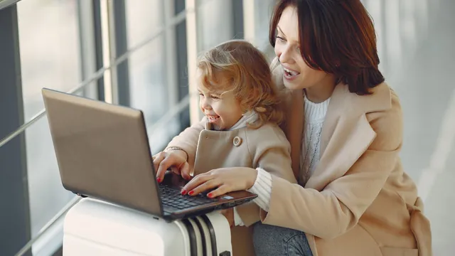 Mutter und Kind mit Laptop auf einem Koffer – mit Familie und Gepäck zum Flughafen Köln/Bonn