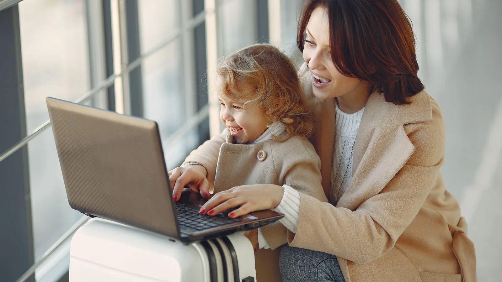 Mother and child with a laptop on a suitcase – with family and luggage to Cologne/Bonn Airport