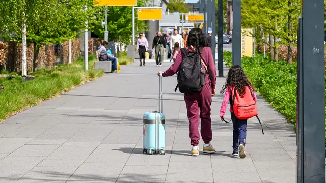Mutter und Tochter mit Koffer auf dem Weg zum Terminal – mit Familie und Gepäck zum Flughafen München