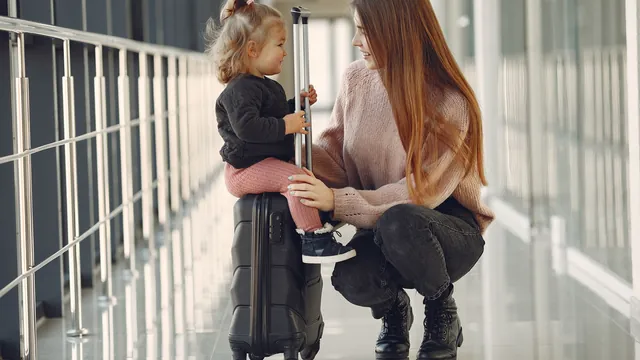 Mutter und Kind auf einem Koffer im Flughafengang – mit Familie und Gepäck zum Flughafen Nürnberg