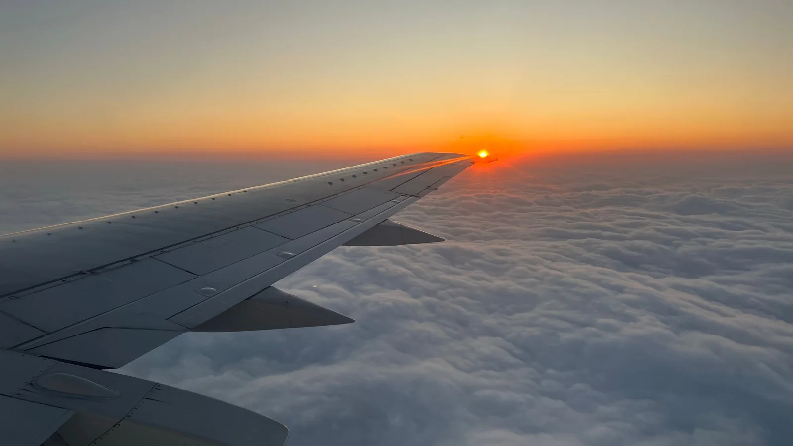Aile d'avion au-dessus d'une mer de brouillard au lever du soleil – stationnement pour un vol matinal à l'aéroport de Hanovre