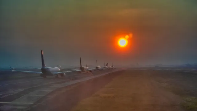 Flugzeuge in einer Reihe auf dem Rollfeld bei tief stehender Sonne – Parken für den Frühflug am Flughafen Memmingen