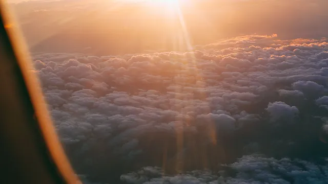 Sonnenstrahlen über den Wolken, gesehen aus dem Flugzeugfenster – Parken für den Frühflug am Flughafen Nürnberg
