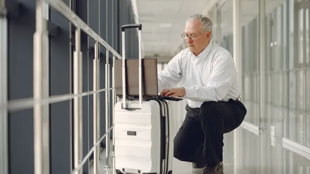 Geschäftsmann arbeitet am Laptop auf seinem Koffer – Parken für Geschäftsreisen am Flughafen Dortmund