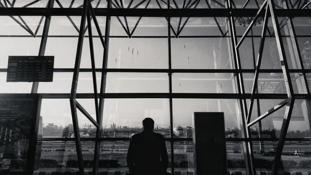 Silhouette eines Reisenden vor einer Fensterfront – Parken für Geschäftsreisen am Flughafen Memmingen