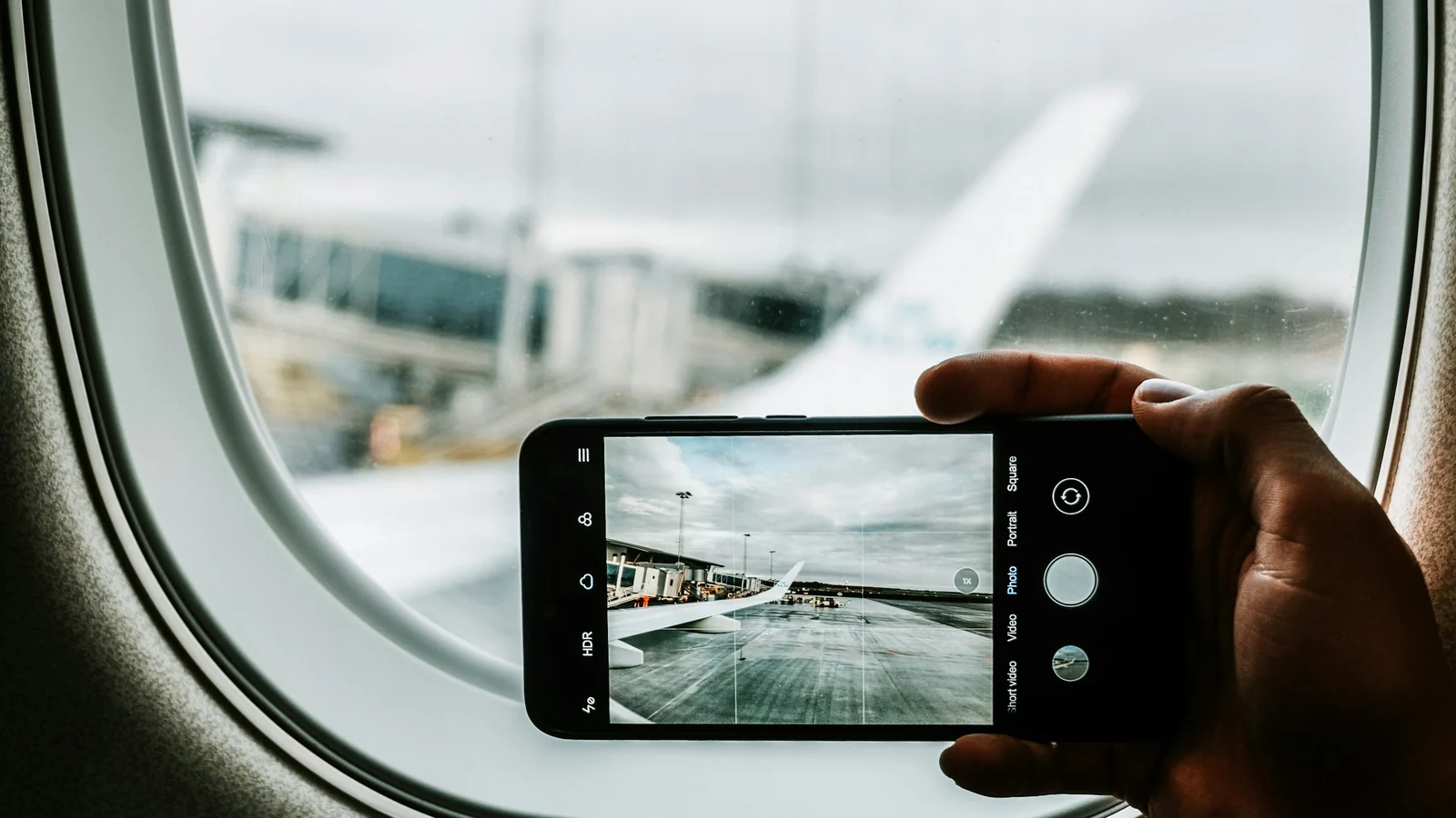 Smartphone am Flugzeugfenster – Parkplatz am Flughafen Düsseldorf kurzfristig buchen