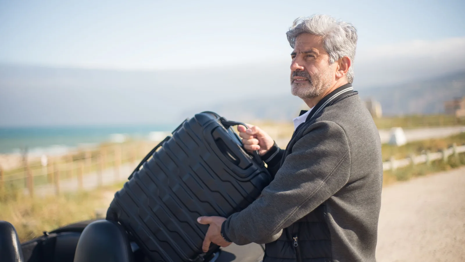 Man loading a suitcase into a convertible – long-term holiday parking at Nuremberg Airport