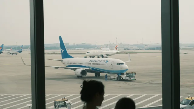 Eltern und Kind schauen durch die Terminalscheibe auf ein Flugzeug – mit Kindern am Flughafen Düsseldorf