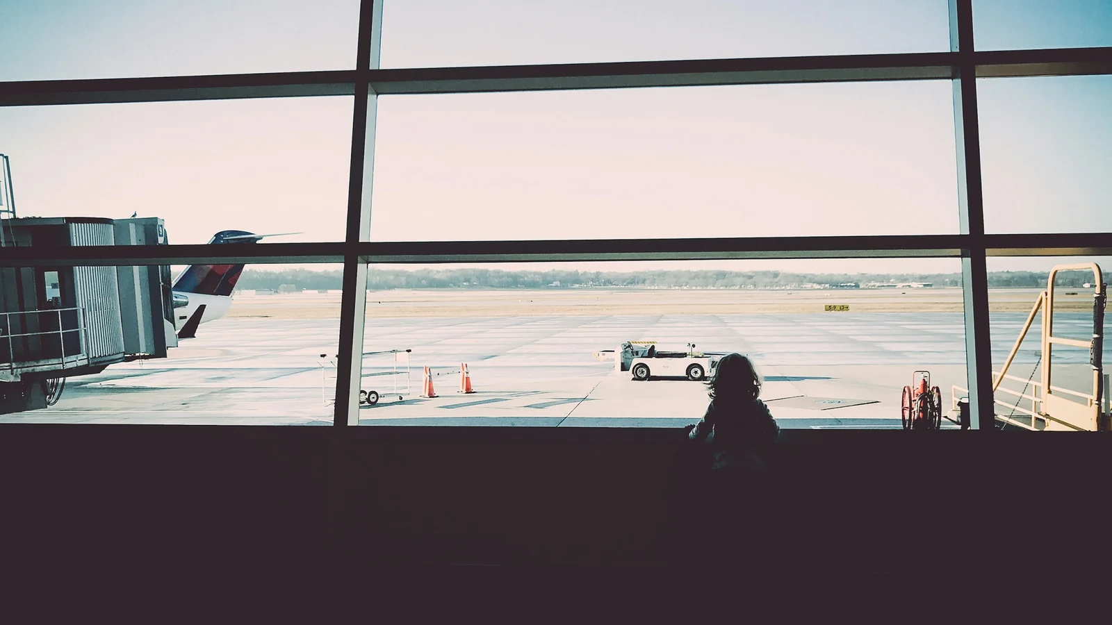 Kind schaut durch die Terminalscheibe auf das Vorfeld – mit Kindern am Flughafen Frankfurt
