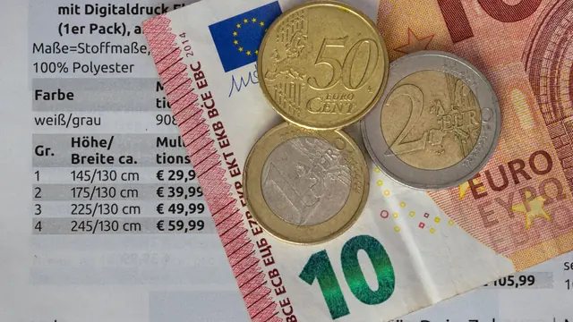 Euro-Münzen und Euro-Scheine auf einer Preisliste – Parkkosten am Flughafen Berlin (BER) vergleichen