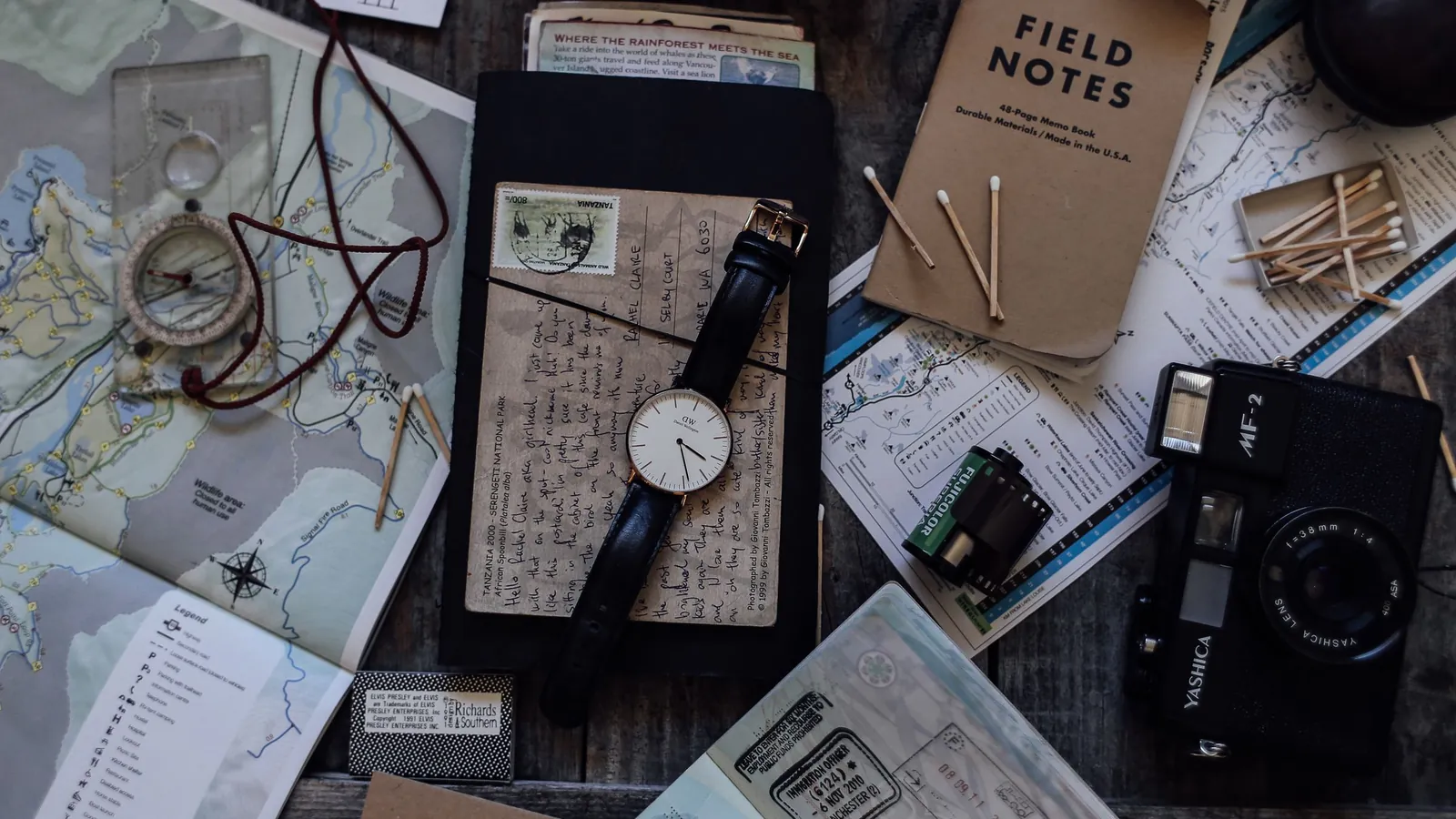 Accessoires de voyage avec cartes, appareil photo et montre sur une table – réserver un parking à l'aéroport de Stuttgart