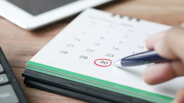 Stift zeigt auf ein markiertes Datum im Kalender – Parkplatz am Flughafen Memmingen stornieren oder umbuchen