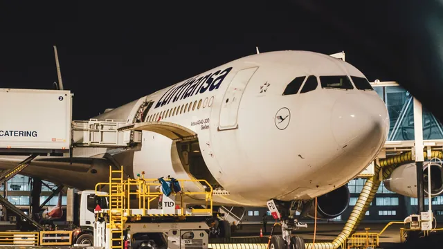 Beleuchtetes Flugzeug am Terminal bei Nacht mit Bodenfahrzeugen – späte Ankunft am Flughafen Stuttgart