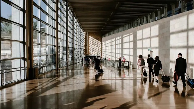 Reisende mit Koffern in einem langen Terminalgang – Streik am Flughafen Frankfurt