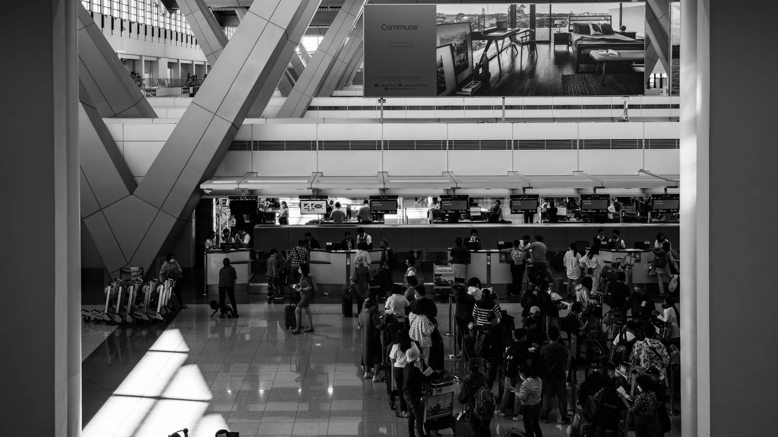 Check-in-Bereich mit Reisenden in Schwarz-Weiß – Orientierung im Terminal am Flughafen Dortmund